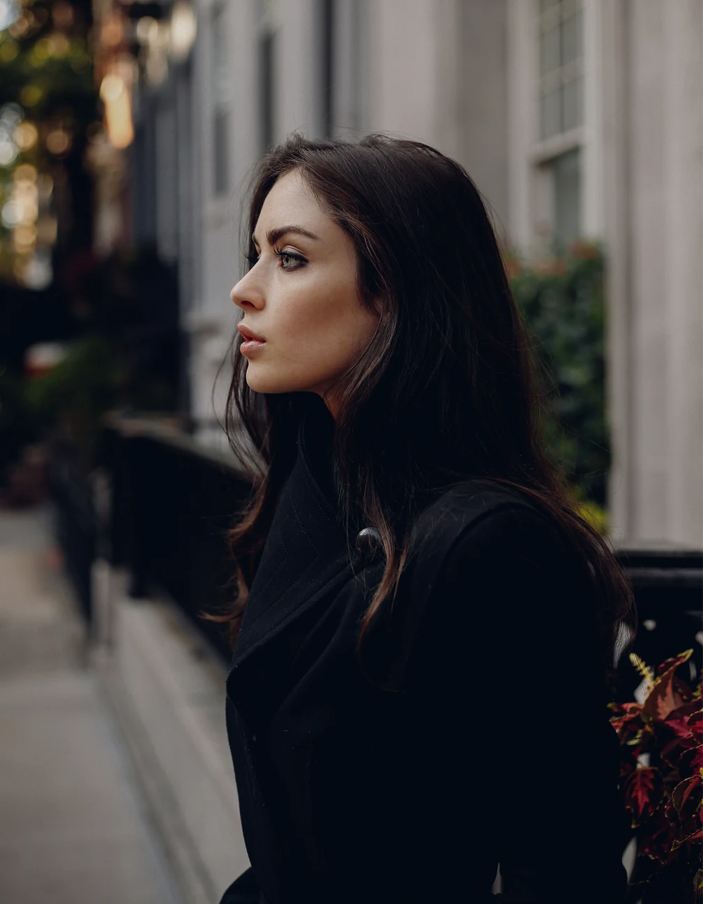 Portrait of Alex Holder on a city street, in profile, wearing a dark coat.